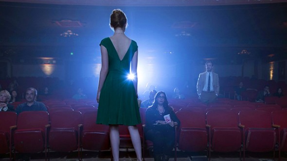 Emma stone éclairée par une lumière de salle de cinéma